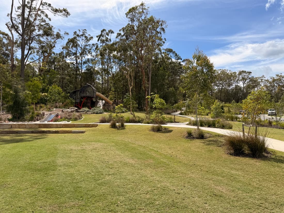 A council reserve after mowing: cut sward with mowing stripes, a shared path and plantings running back to the tree line.